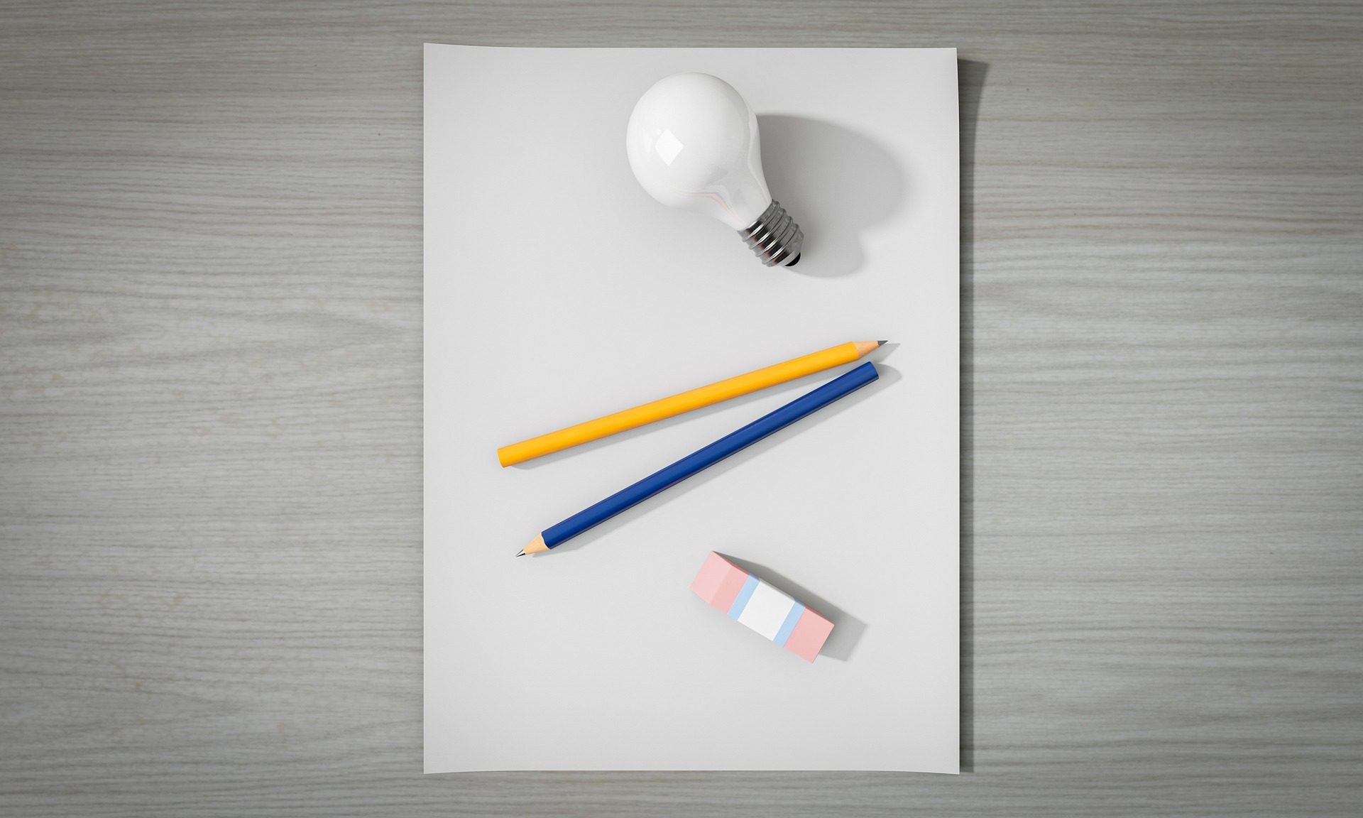Verschiedene Gegenstände auf einem Blatt Papier: Ein Glühbirne, 2 Bleistifte, 1 Radiergummi.